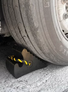 A heavy-duty rubber wheel stopper correctly engaging a commercial truck tyre below the wheel centre line to prevent infrastructure damage.