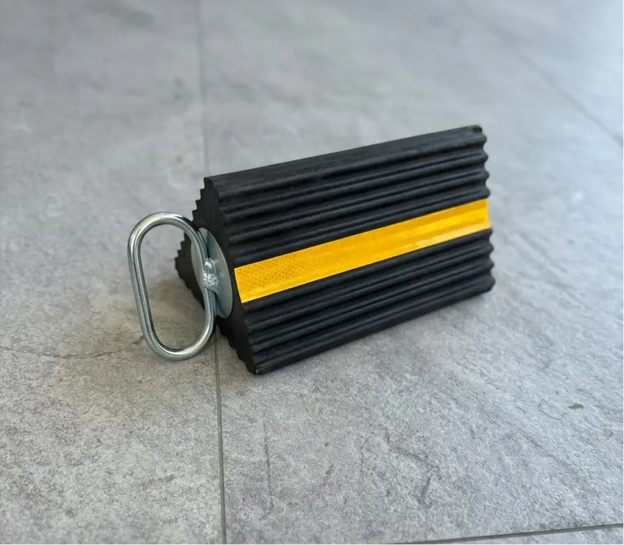 Heavy duty steel wheel chock securing heavy plant machinery on sloped site ground