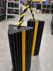 A pair of compact rubber aircraft wheel chocks connected by a heavy-duty braided rope handle for easy ramp handling.